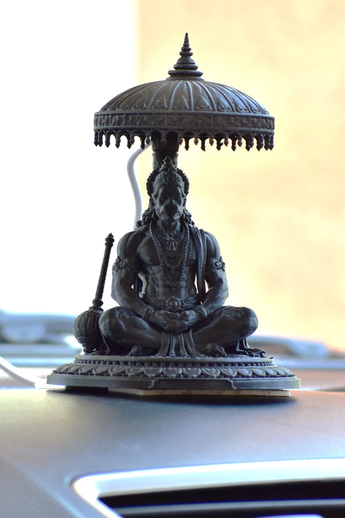 Statue of a seated figure with an umbrella on a car's sunshade